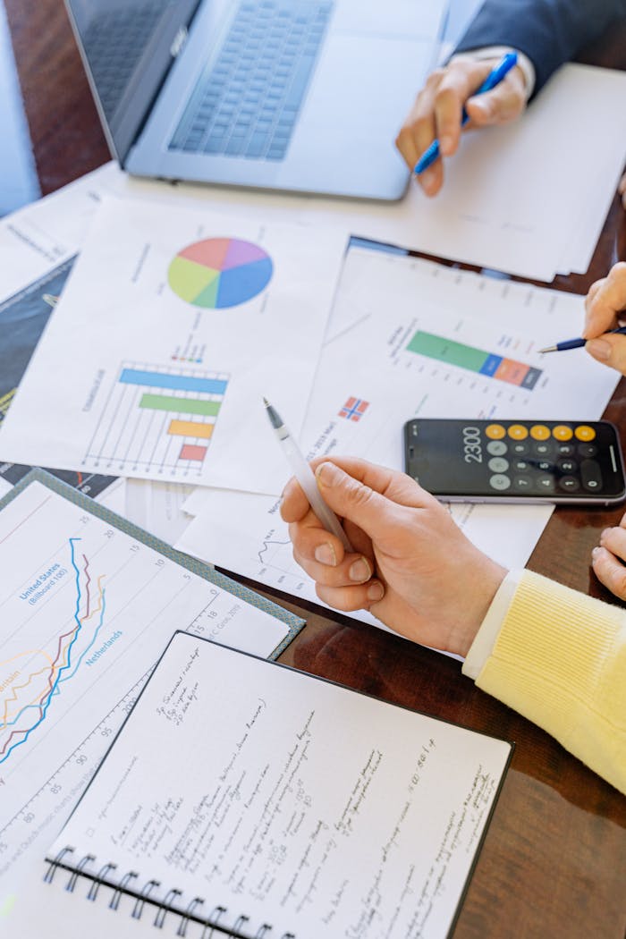 hero-img-01 A close-up of businesspeople analyzing financial data and charts during a meeting.