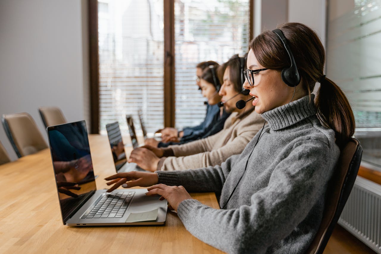 why-choose-us Professional customer service team working in a modern office setting with headsets and laptops.